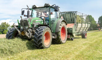 Ein Mann sammelt mit einem Traktor die gemähten Futterpflanzen.