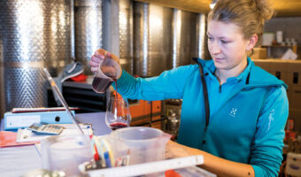 Weintechnologin beim Abfüllen einer Weinprobe in ein Weinglas.