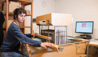 Eine Frau webt Stoffe mit einem Handwebstuhl.