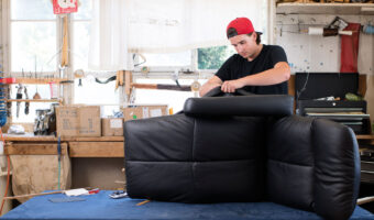 Ein Mann bezieht ein Polstermöbel mit Leder.