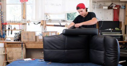 Ein Mann bezieht ein Polstermöbel mit Leder.