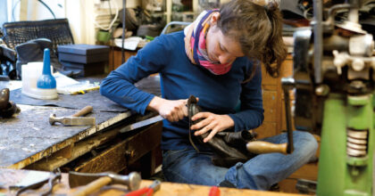 Eine Frau befestigt die Sohle an einem Stiefel.