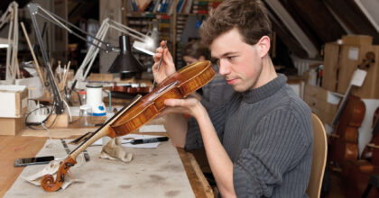 Ein Mann führt in einem Atelier Wartungsarbeiten an einer Geige durch.