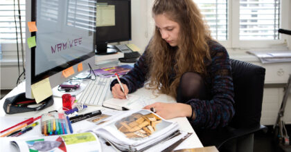 Eine Frau erstellt in einer Büroumgebung eine Skizze in ihrem Skizzenbuch.