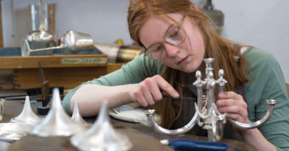 Eine Frau schraubt ein silbernes Objekt zusammen.