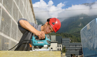 Ein Mann schneidet auf der Baustelle ein Holzstück mit einer Stichsäge.