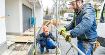 Zwei Männer überprüfen mit einer Wasserwaage ob das Baugerüst waagrecht steht.
