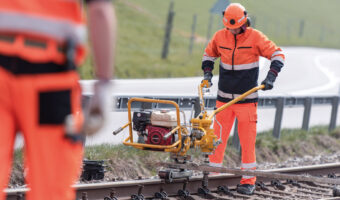 Ein Mann befestigt das Gleis mit Schwellenschrauben.