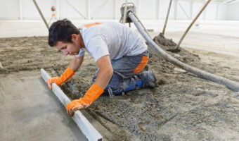 Ein Mann verteilt mit einer Abziehlatte eine Materialmischung.