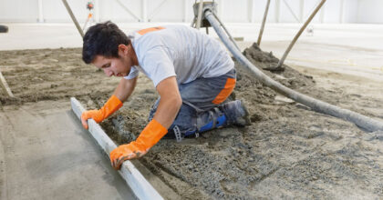 Ein Mann verteilt mit einer Abziehlatte eine Materialmischung.