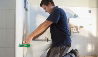 Ein Mann montiert eine Toilettenschüssel an der Wand.