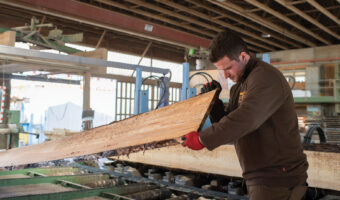 Ein Mann begutachtet ein rohes Holzbrett.