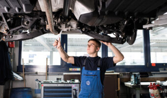 Ein Mann führt in einer Autowerkstatt Wartungsarbeiten an einem Fahrzeug durch.
