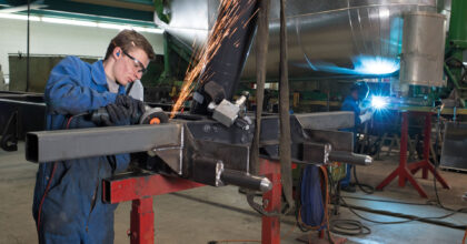 Ein Mann schleift ein quadratisches Stahlrohr.