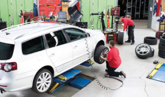 Ein Mann in einer Garage wechselt das Rad eines Fahrzeugs aus.