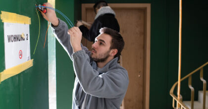 Ein Mann verlegt Kabel im Treppenhaus eines Gebäudes.