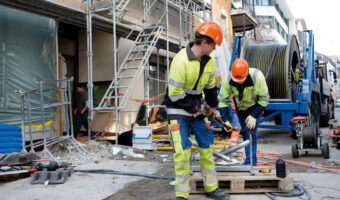Zwei Männer montieren auf einer Baustelle ein Netzkabel.
