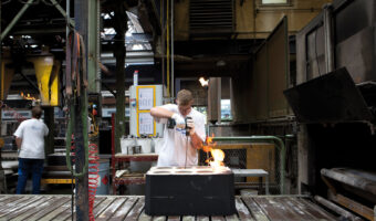 Ein Mann in einer Giesserei bohrt in eine Gussform.