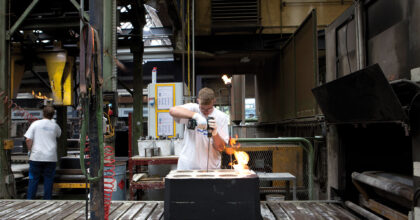 Ein Mann in einer Giesserei bohrt in eine Gussform.