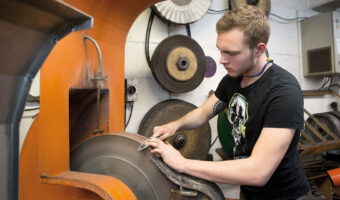 Ein Mann schärft die Klinge eines Messers mit einer Messerschleifmaschine.