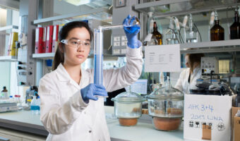 Eine Frau mit Schutzkleidung führt einen Laborversuch durch.