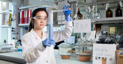 Eine Frau mit Schutzkleidung führt einen Laborversuch durch.