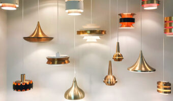 Mehrere Hängelampen in verschiedenen Formen und Farben hängen leuchtend nebeneinander.