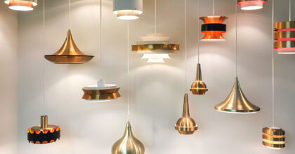 Mehrere Hängelampen in verschiedenen Formen und Farben hängen leuchtend nebeneinander.