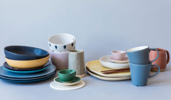 Auf einem Tisch stehen diverse gestapelte Teller, Tassen und Kännchen aus Keramik.
