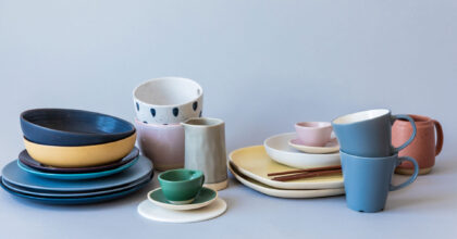 Auf einem Tisch stehen diverse gestapelte Teller, Tassen und Kännchen aus Keramik.