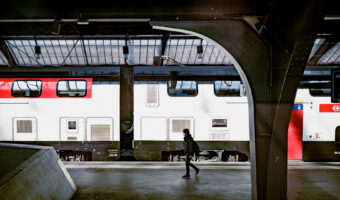 Person auf einem Perron am Bahnhof vor einem stehenden Zug.