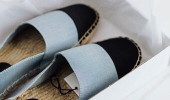 Offene Espadrilles liegen auf Seidenpapier in einem Schuhkarton.