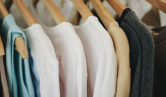 Verschiedene Damenoberbekleidung hängt an Holzkleiderbügeln.