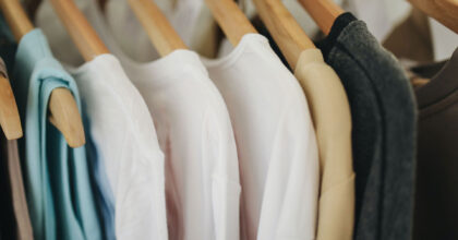 Verschiedene Damenoberbekleidung hängt an Holzkleiderbügeln.