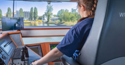 Kapitänin beim Lenken eines Schiffs auf einem Fluss.