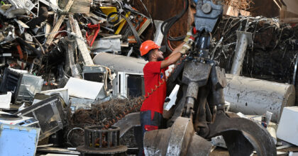 Ein Mann in einer Recyclinghalle wartet eine Greifvorrichtung.