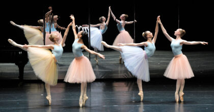 Vier Ballerinas tanzen in Zweiergruppen vor einem Spiegel.