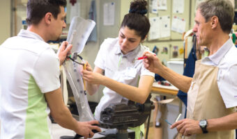 Eine Frau und zwei Männer fertigen eine Beinprothese an.