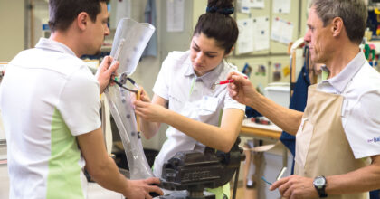 Eine Frau und zwei Männer fertigen eine Beinprothese an.