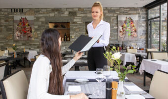 Eine Frau reicht einem weiblichen Gast die Karte.