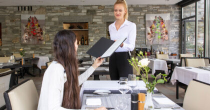 Eine Frau reicht einem weiblichen Gast die Karte.