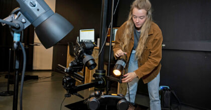 Eine Frau richtet bei einer vorbereiteten Aufnahme das Licht perfekt aus..