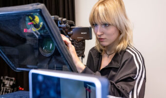 Eine Frau stellt eine Filmkamera ein.