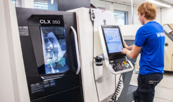 Ein Mann steht vor einer Maschine und tippt etwas auf einem Touchscreen.