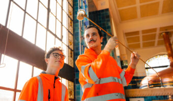 Zwei Personen betrachten eine entnommene Bierprobe.