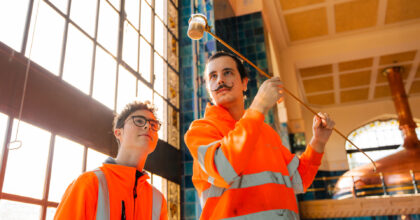 Zwei Personen betrachten eine entnommene Bierprobe.