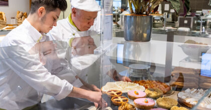 Zwei Männer drapieren süsse Köstlichkeiten in einer Vitrine.