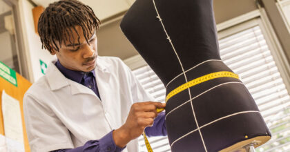 Ein Mann misst mit einem Centimetermass an einer Schneiderpuppe den Taillenumfang.