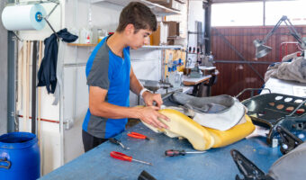 Ein Mann entfernt an einem ausgebauten Autositz den alten Bezug.