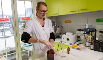 Eine Frau in weissem Arbeitskittel mixt eine Tinktur zusammen.